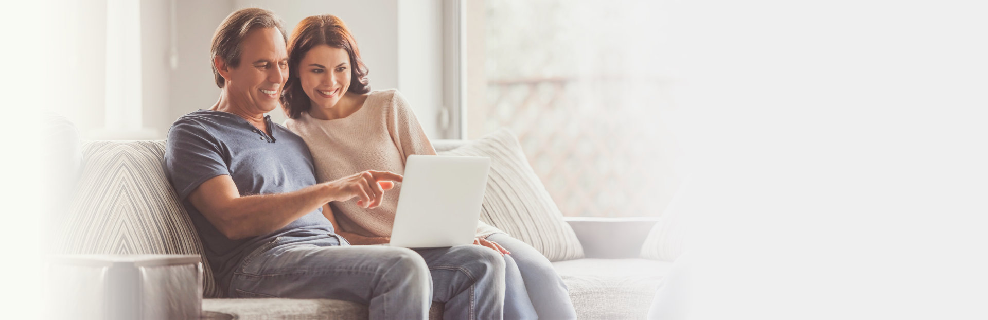 couple sitting in the couch while using laptop